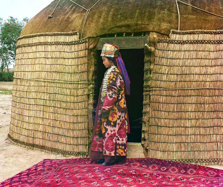 Turkman woman at the entrance to a yurt, dressed in traditional clothing and jewelry
